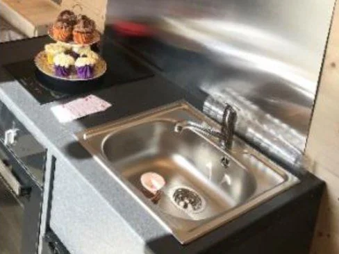 Fitted kitchen unit with sink and induction hob inside a Low Road Nursery glamping pod
